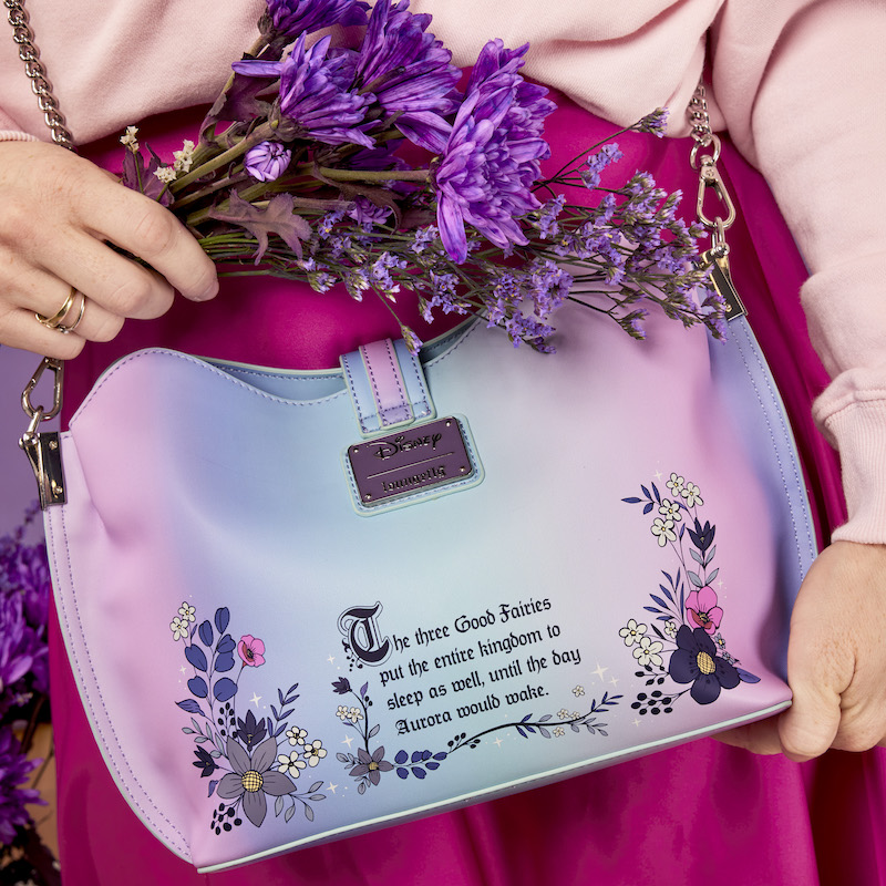 Image of someone holding the Loungefly Disney Sleeping Beauty 65th Anniversary Floral Ombre Crossbody Bag and showing the back that has flowers and a quote on it 
